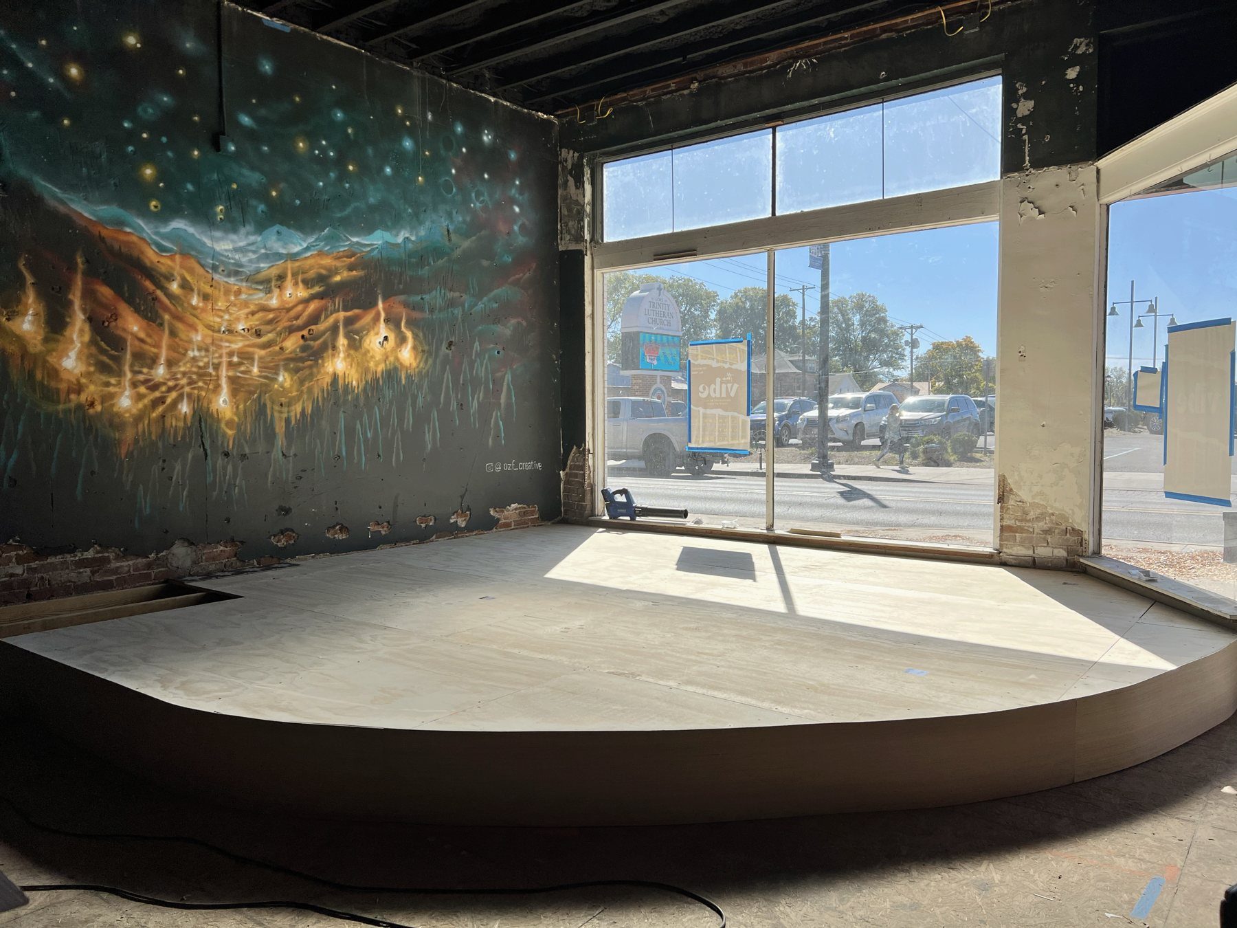 The new stage at The Vibe mid-buildout, with a starry mural on the wall and big front windows onto Broadway